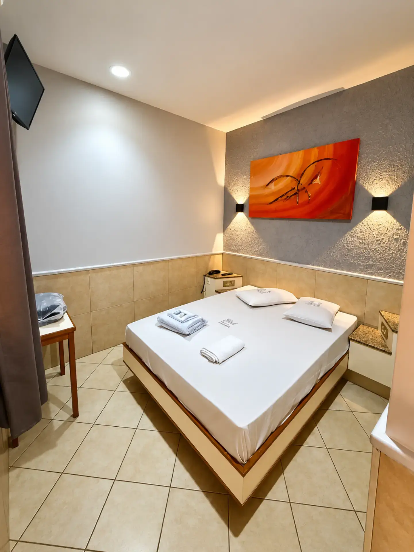 Suite with full bed, fresh towels and warm lighting